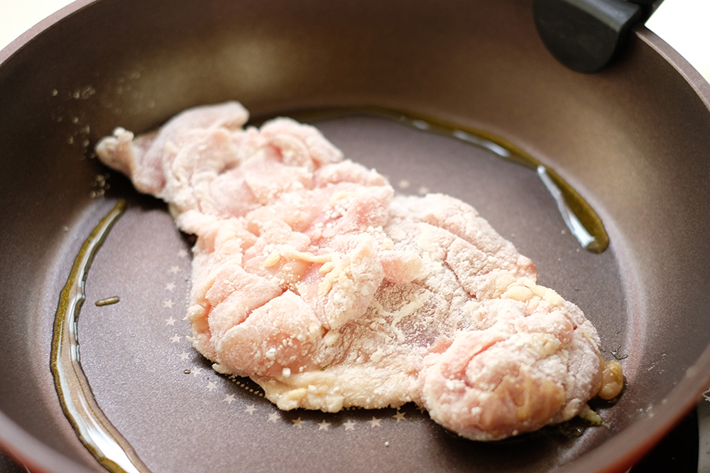 片栗粉をまぶした鶏肉をフライパンで焼く