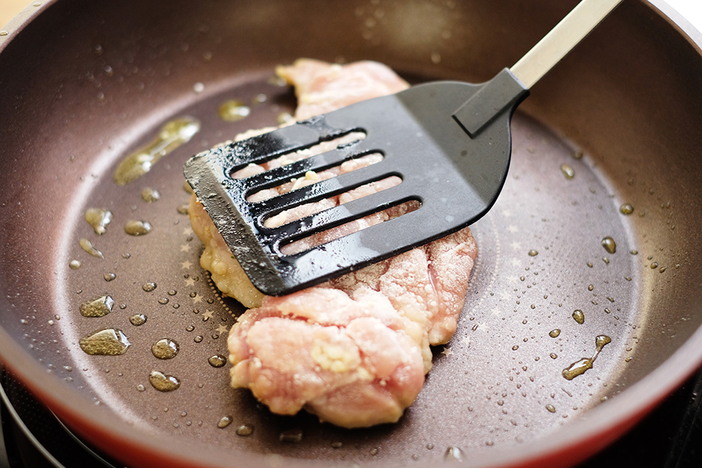 フライ返しで鶏肉をフライパンに押し付けてよく焼く